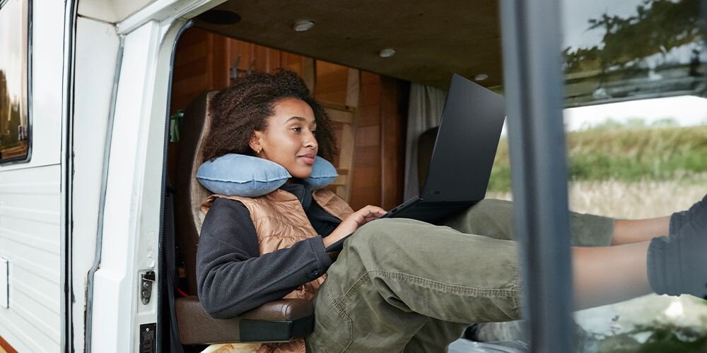 Kobieta leżąca w przyczepie kempingowej używająca laptopa ASUS ProArt P16, komfortowe wnętrze pojazdu rekreacyjnego z poduszką podróżną - StoryCube i MuseTree