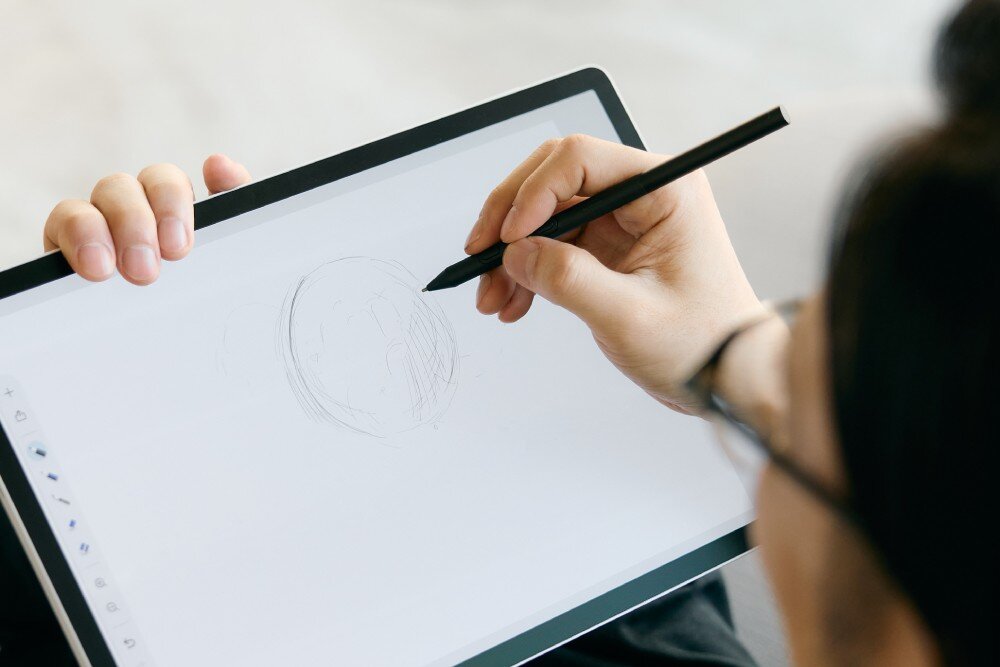 Osoba rysuje na tablecie graficznym za pomocą rysika. Na ekranie widoczny jest szkic okręgu.