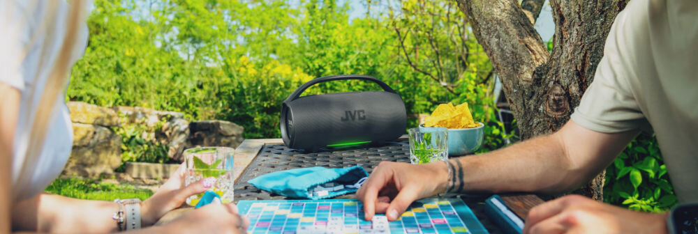 Głośnik mobilny JVC XS-E524B akumulator 2500 mAh 20 godzin pracy ładowanie USB-C, głośnik stojący na stoliku w plenerze