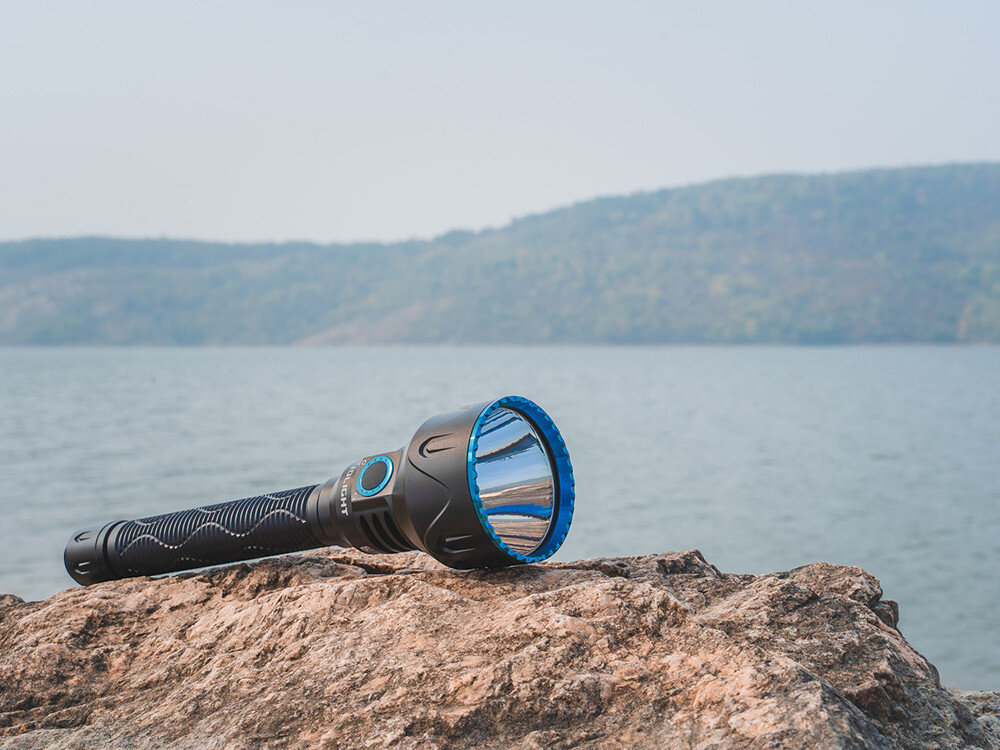 Latarka OLIGHT Javelot Turbo 2 OL003991 Czarny, siła, światło, latarka, moc, Latarka Olight Javelot Turbo 2 Black leży na kamieniu przy jeziorze, niebieski bezel, plener.
