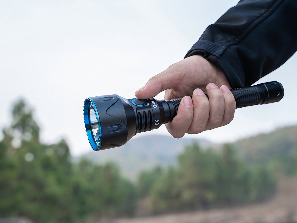 Latarka OLIGHT Javelot Turbo 2 OL003991 Czarny, aluminium, lekkość, odporność, ergonomia, Olight Javelot Turbo 2 trzymana w dłoni, masywny reflektor z niebieskim wykończeniem, plener.