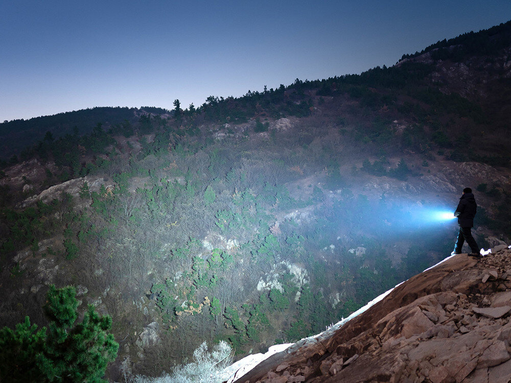 Latarka OLIGHT Baton 3 Pro Max OL000358 Czarny, ergonomia, moc, 2500, światło, Osoba oświetla zbocze góry mocną latarką Olight Baton 3 Pro Max, szeroki snop, nocne warunki.