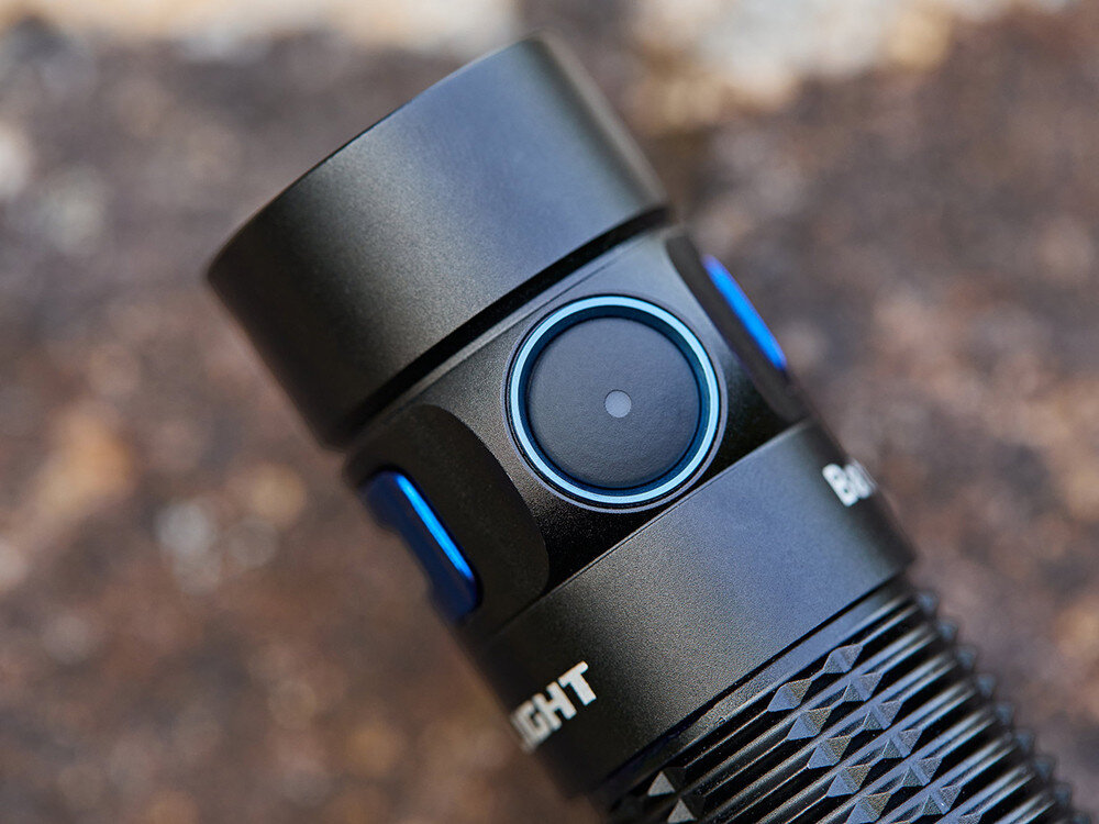 Latarka OLIGHT Baton 3 Pro Max OL000358 Czarny, aluminium, IPX8, chwyt, wytrzymałość, Zbliżenie na włącznik latarki Olight Baton 3 Pro Max z niebieskim pierścieniem, szczegóły detali.