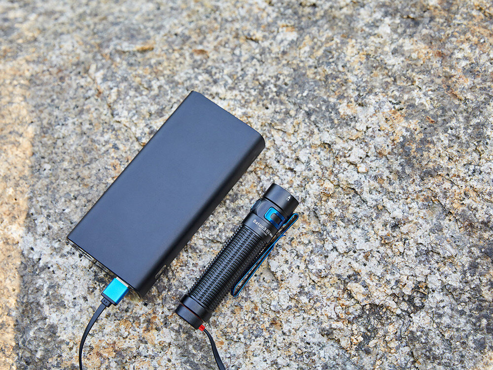 Latarka OLIGHT Baton 3 Pro Max OL000358 Czarny, akumulator, MCC3, wskaźnik, potrząśnięcie, Powerbank ładuje latarkę Olight Baton 3 Pro Max przez kabel magnetyczny, skała podłoże.