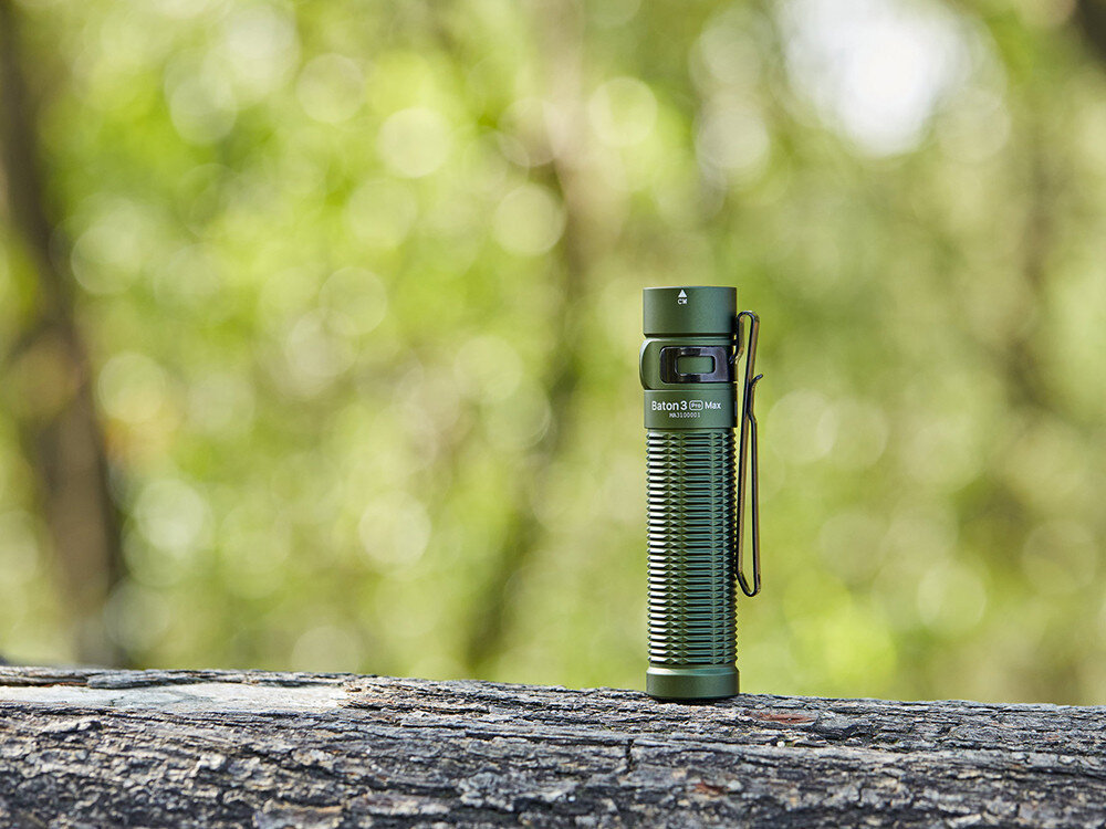 Latarka OLIGHT Baton 3 Pro Max OL001096 Zielony, czujnik, Turbo, bezpieczeństwo, stabilizator, Zielona Baton 3 Pro Max stoi pionowo na grubej gałęzi, wyraziste żebrowanie korpusu.