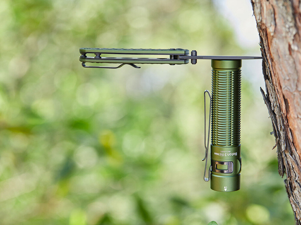 Latarka OLIGHT Baton 3 Pro Max OL001096 Zielony, tryby, stroboskop, czas, uniwersalność, Zielona Olight Baton 3 Pro Max zamocowana stalowym klipsem do gałęzi drzewa, naturalne tło.