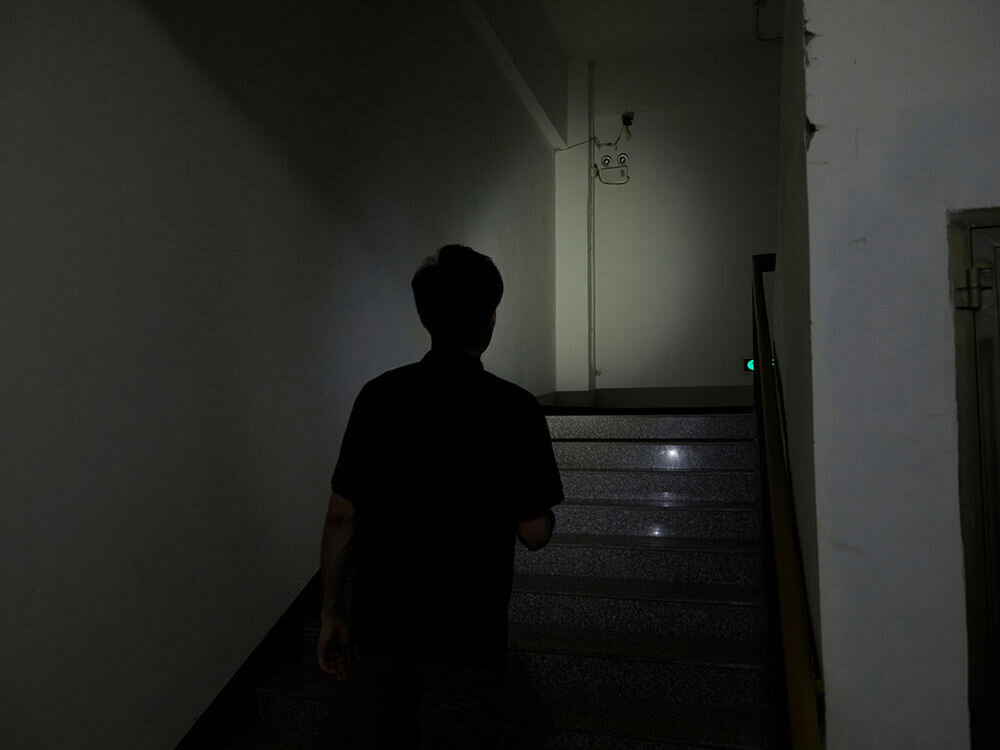 LATARKA OLIGHT BATON 3 PRO CW 1500LM 175M 120 DNI, odpornośc, Powierzchnia, antypoślizgowa, IPX8, wodoodporność, osoba idzie po schodach po ciemku i oświetla drogę latarką