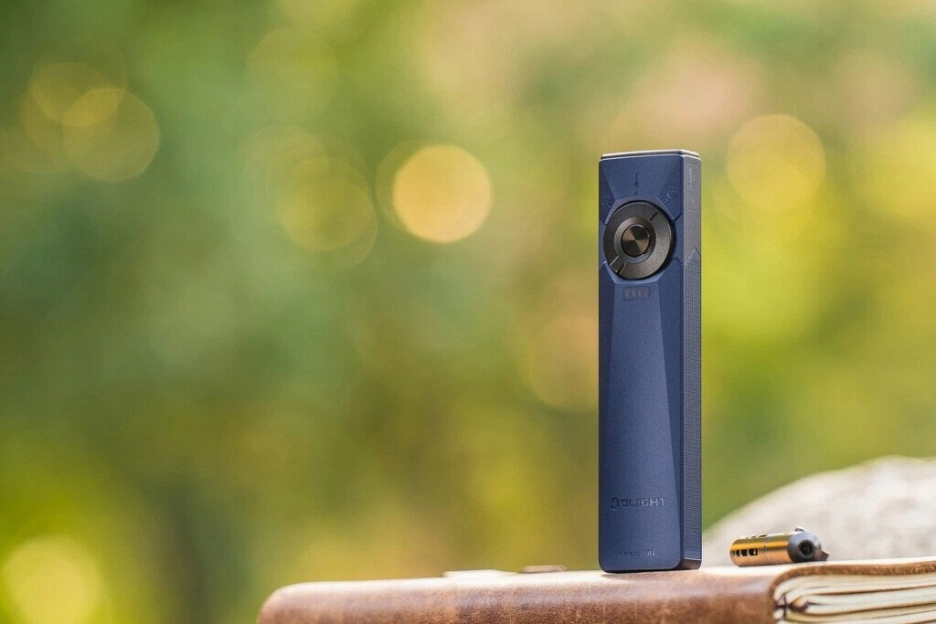 Latarka OLIGHT Arkfeld Ultra UV OL691688 Ciemnoniebieski, latarka, ergonomiczna, EDC, białe światło, Niebieska latarka stoi pionowo na tle bokeh