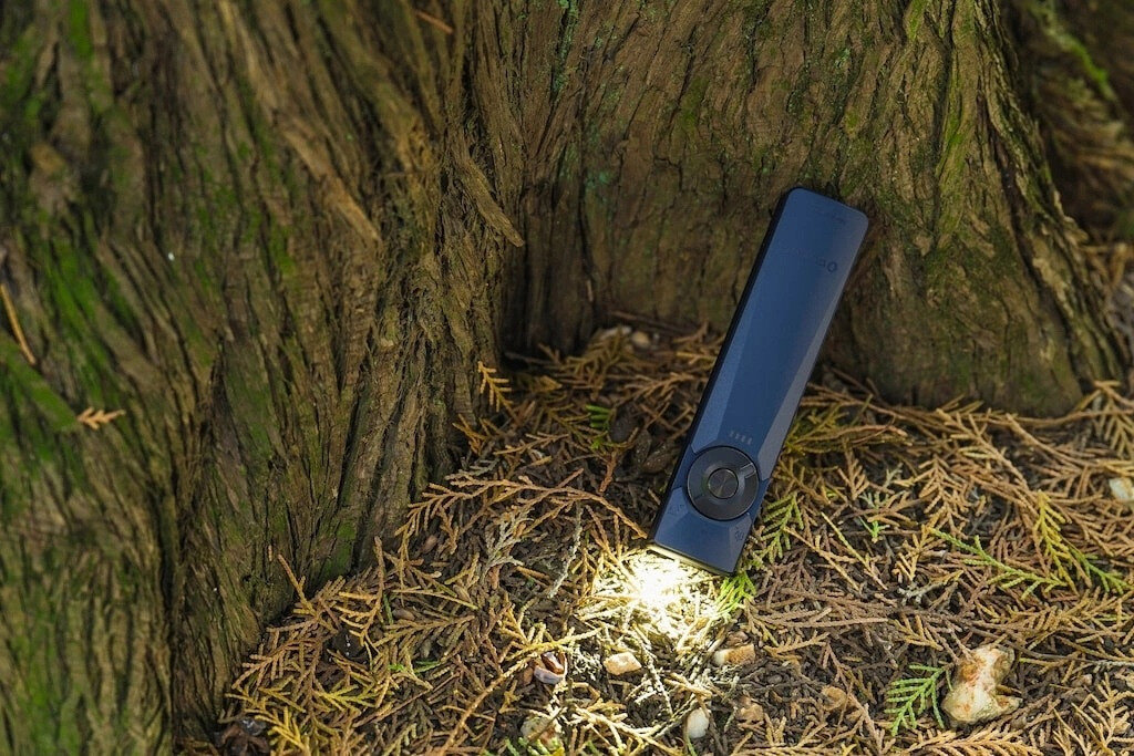 Latarka OLIGHT Arkfeld Ultra UV OL691664 Ciemnoniebieski, elektronika, stabilność, bezpieczeństwo, wydajność, Niebieska latarka świeci u podstawy drzewa