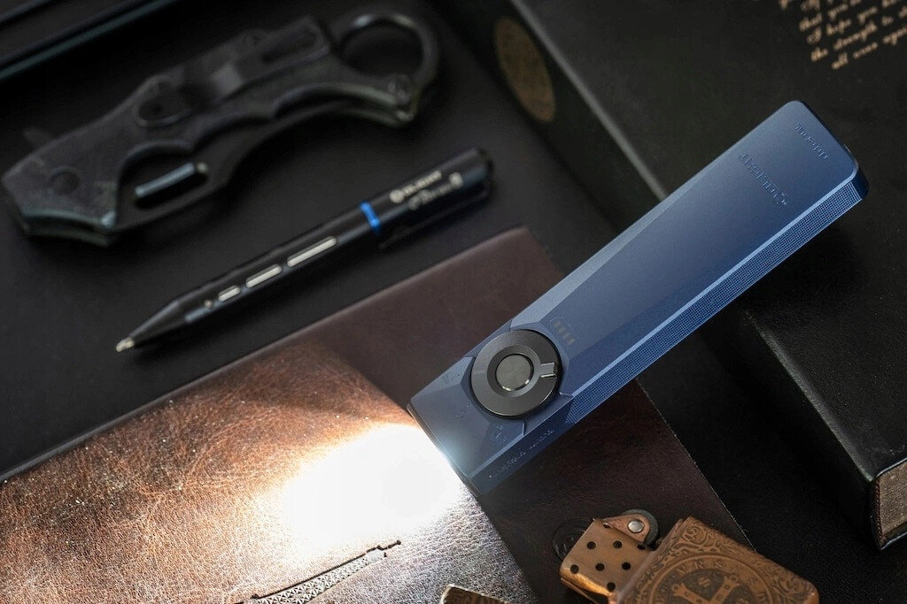 Latarka OLIGHT Arkfeld Ultra UV OL691664 Ciemnoniebieski, rozmiar, lekkość, moc, mobilność, Niebieska latarka świeci na skórzany notes