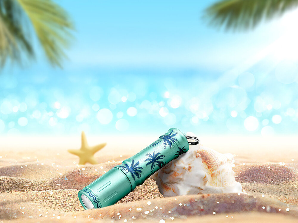 Latarka OLIGHT I3E EOS OL692821 Letnie Palmy Zielony, zasilanie, bateria, dostępność, czas, Limitowana latarka Olight I3E EOS Palmy w kolorze turkusowym oparta o muszlę na piasku, plaża.