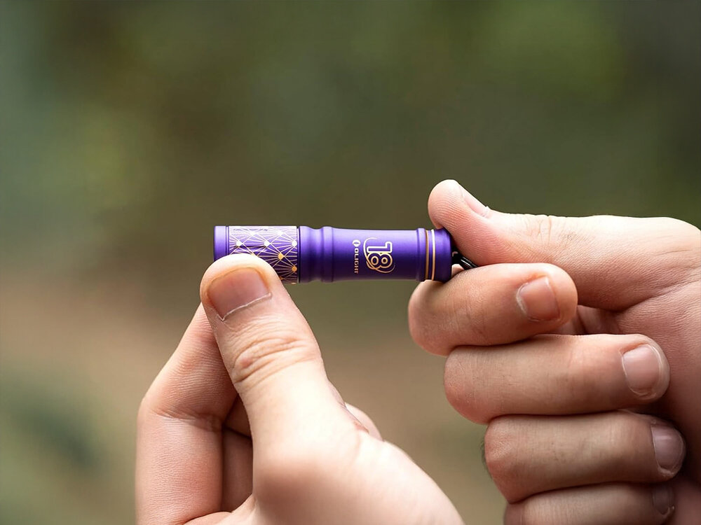 Latarka OLIGHT I3E EOS OL692340 Niebieski, zasilanie, bateria, dostępność, czas, Limitowana latarka Olight I1R 2 PRO fioletowa, trzymana w dwóch dłoniach, matowe wykończenie.