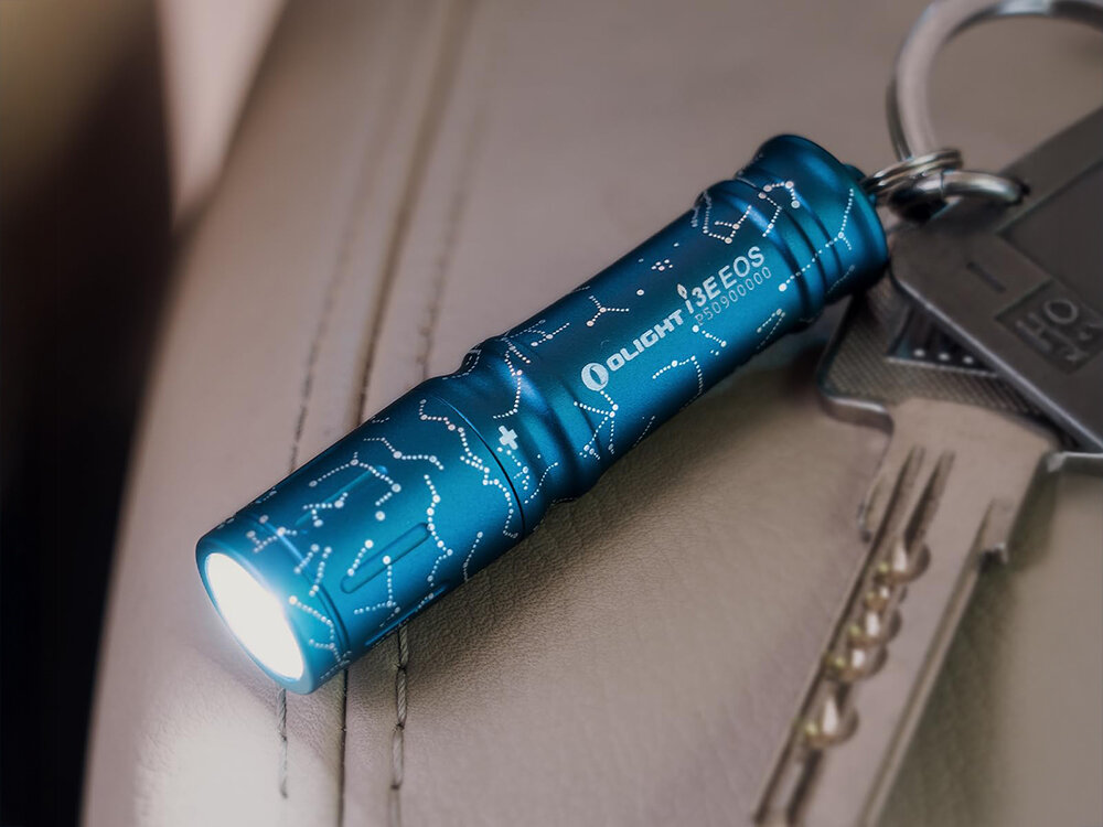 Latarka OLIGHT I3E EOS OL693712 Astral Cobalt Niebieski, miniaturowa, jasność, 90 lumenów, codzienne, Olight I3E EOS Constellation niebieska, brelok przy kluczach, świeci, skóra jasny fotel, makro.