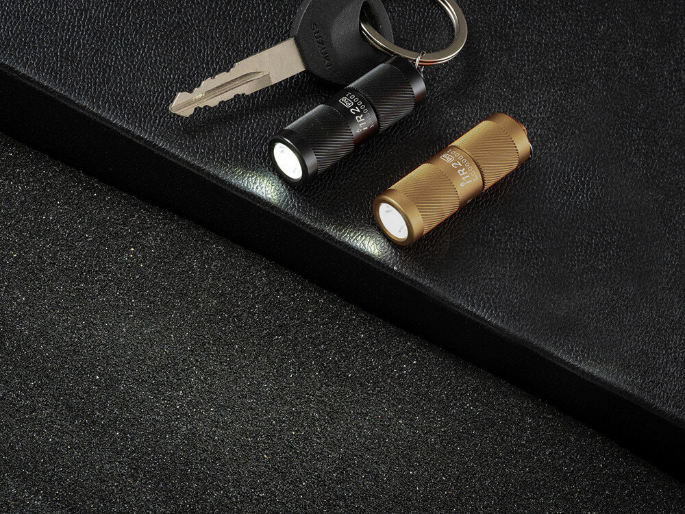 Latarka OLIGHT I1R II EOS Kit, aluminium, anodyzacja, IPX8, odporność, Dwie miniaturowe latarki Olight I1R 2 EOS, brelok, klucze, czarna i złota, czarne tło.