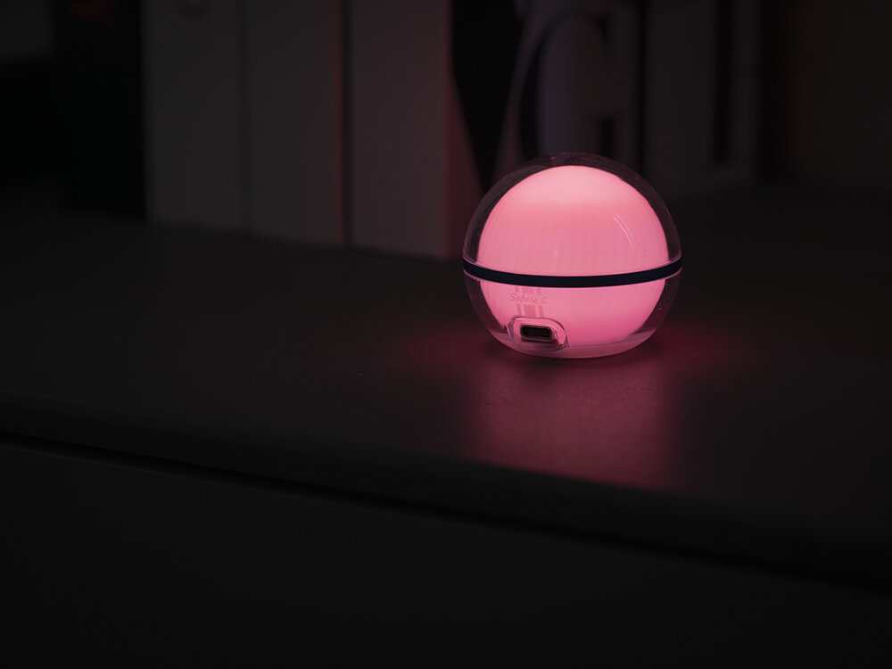 Lampa kempingowa OLIGHT Sphere C OL692302, Oświetlenie 360, bez martwych, lampka nocna, dekoracyjna, Lampka Olight Sphere świeci na różowo, nocny klimat, czarne tło.