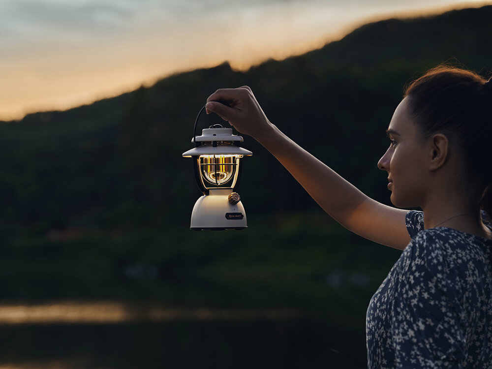 Latarka OLIGHT OL126177 Latarnia biwakowa, uchwyt, podstawa, kemping, ogród, Kobieta trzyma latarnię nad brzegiem jeziora