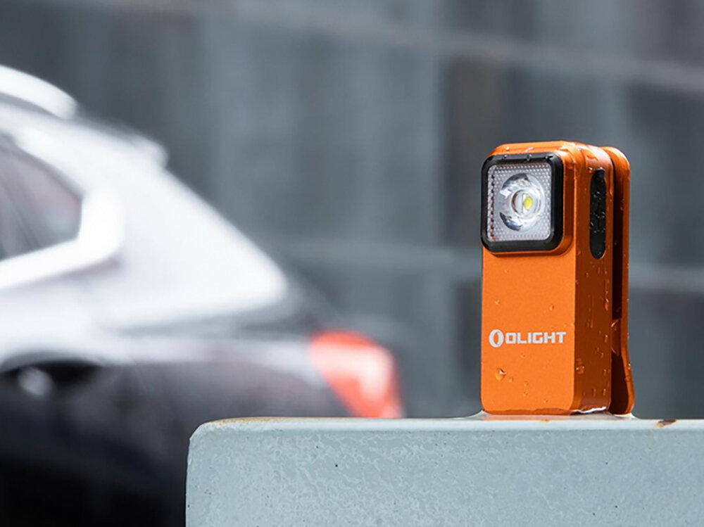 Latarka OLIGHT Oclip OL005483 Pomarańczowy, EDC, mocna, praktyczna, ergonomiczna, Pomarańczowa Oclip w deszczu na betonowej barierze