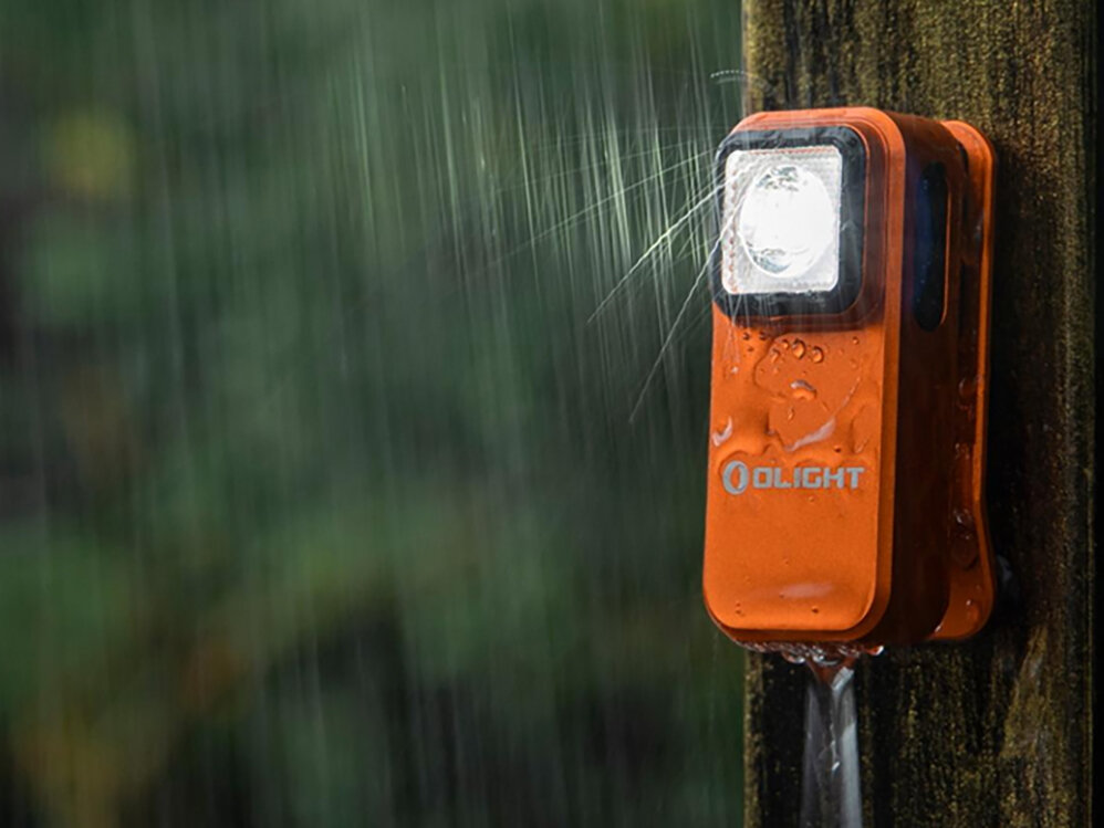 Latarka OLIGHT Oclip OL005483 Pomarańczowy, aluminium, anodyzacja, odporność, IPX5, Wodoodporna Oclip w deszczu na drewnianym słupie