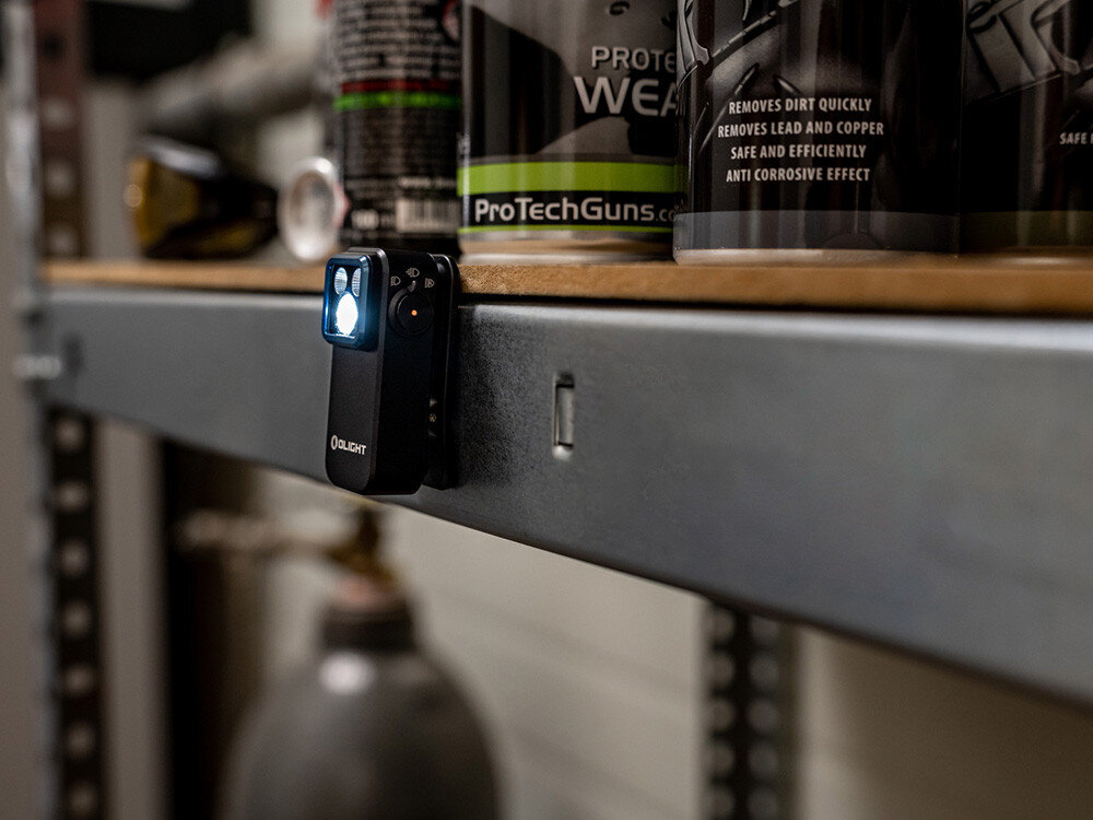 Latarka OLIGHT OL004547, magnes, klips, montaż, linka, Latarka Oclip Pro zamocowana na metalowej półce, magnes mocujący, warsztat, puszki.