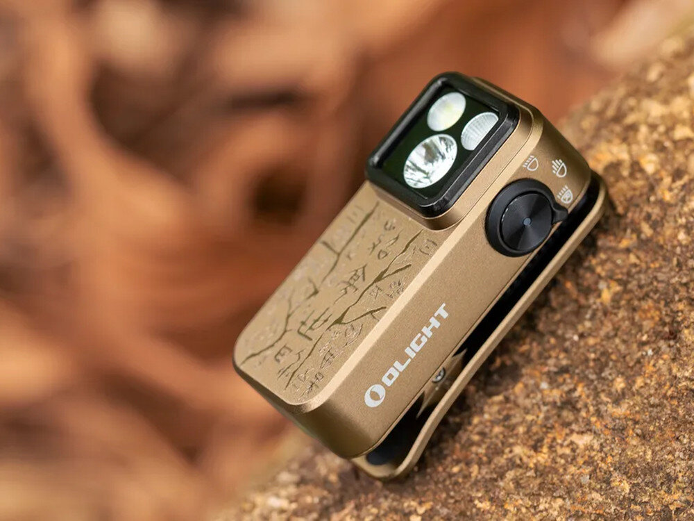 Latarka OLIGHT OL693118, trzy tryby, wszechstronna, lekka, do awaryjnych, Oclip Pro Ancient Script, złoto, leży na kamieniu, grawer, wytrzymała i designerska obudowa.