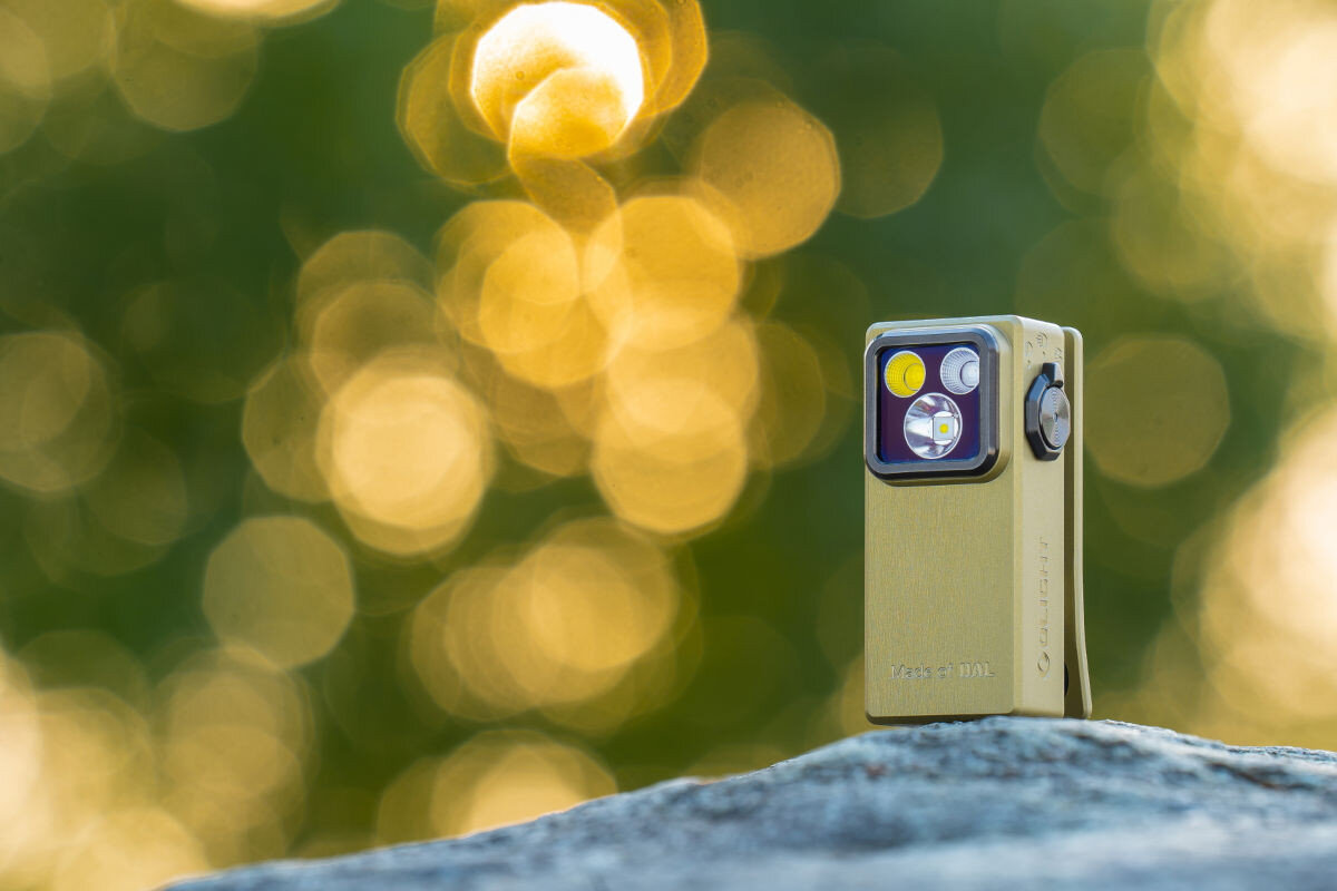 Latarka OLIGHT OL691985, EDC, mocna, wszechstronna, ergonomia, Zielona Oclip Ultra stojąca na skale o zmierzchu