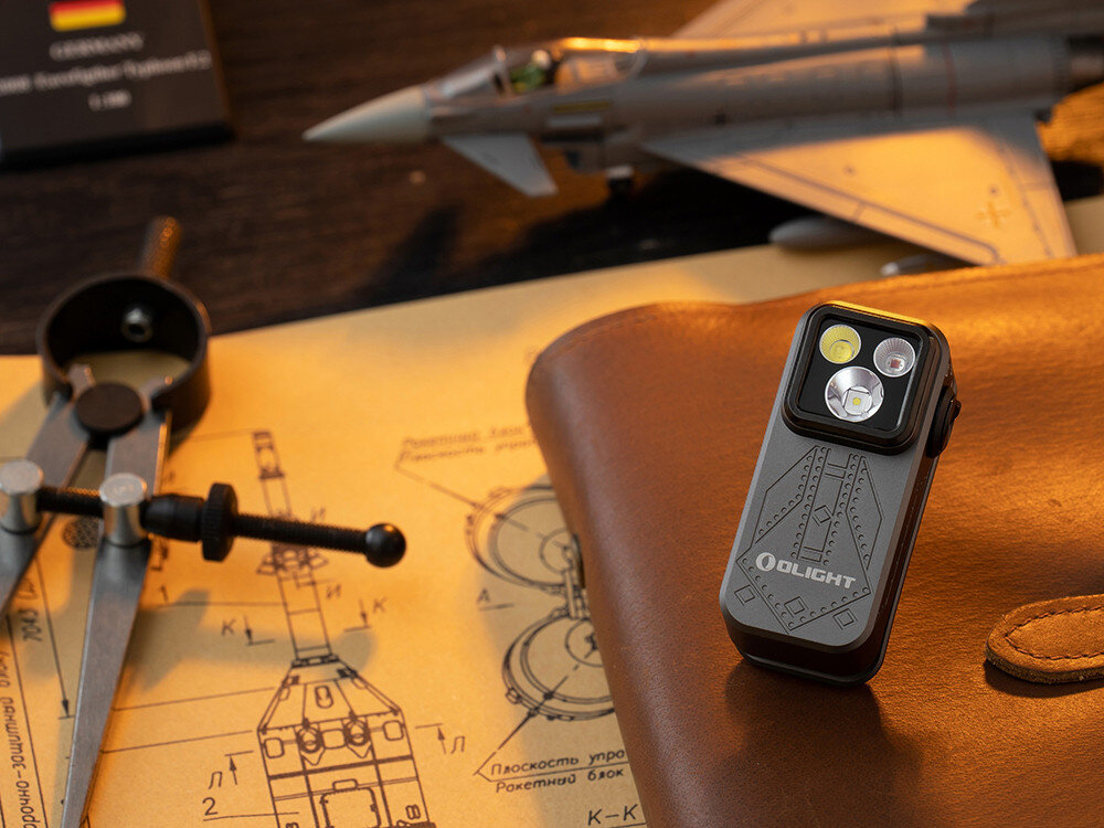 Latarka OLIGHT OL693934, trzy tryby, wszechstronna, lekka, do awaryjnych, Oclip Pro w wersji czarnej na tle projektu technicznego i modelu samolotu, styl industrialny.