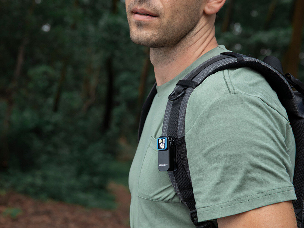 Latarka OLIGHT OL693934, lekka, kieszonkowa, transport, solidna, Oclip Pro wpięta w szelki plecaka, turysta w lesie, łatwe przenoszenie latarki.