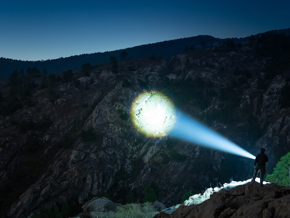 Latarka OLIGHT Marauder Mini QL691626 Piaskowy, światło, EDC, outdoor, uniwersalność,  Wąski, skupiony strumień światła Marauder Mini oświetla ścianę skalną daleko w górach nocą.