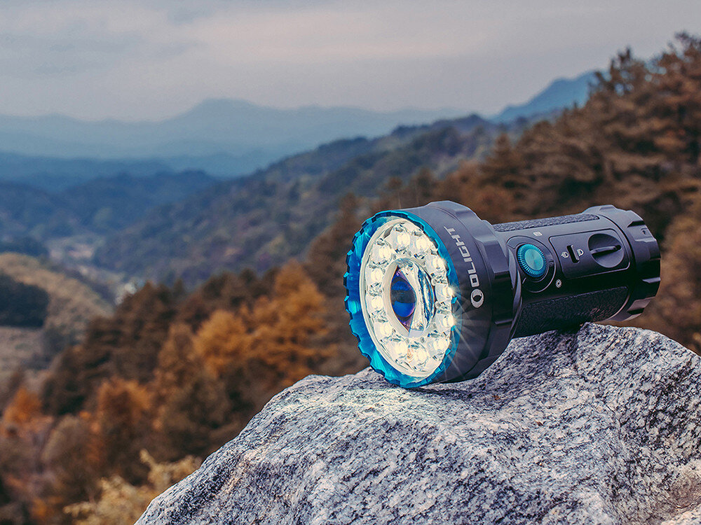 Latarka OLIGHT Marauder 2 QL121615, czujnik, pokrętło, blokada, stroboskop, Marauder 2 leży na skale, góry w tle