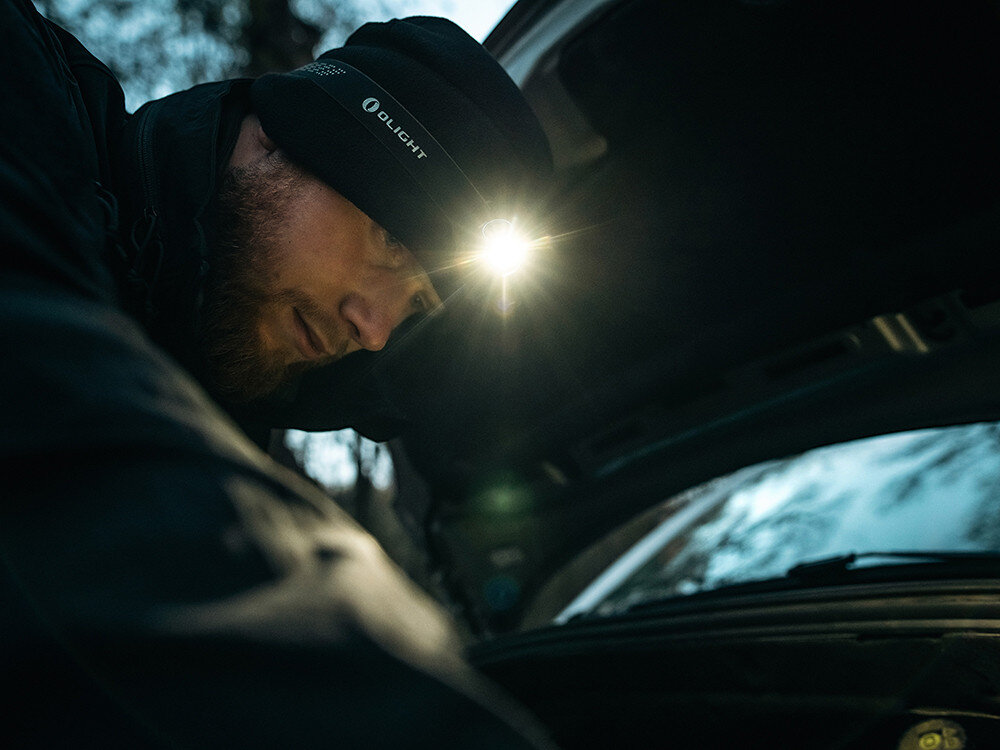Latarka czołowa OLIGHT Perun 2 Mini QL000648, ergonomia, moc, zasilanie, światło, Mechanik w czapce Olight naprawia auto wieczorem, jasna czołówka oświetla komorę silnika.