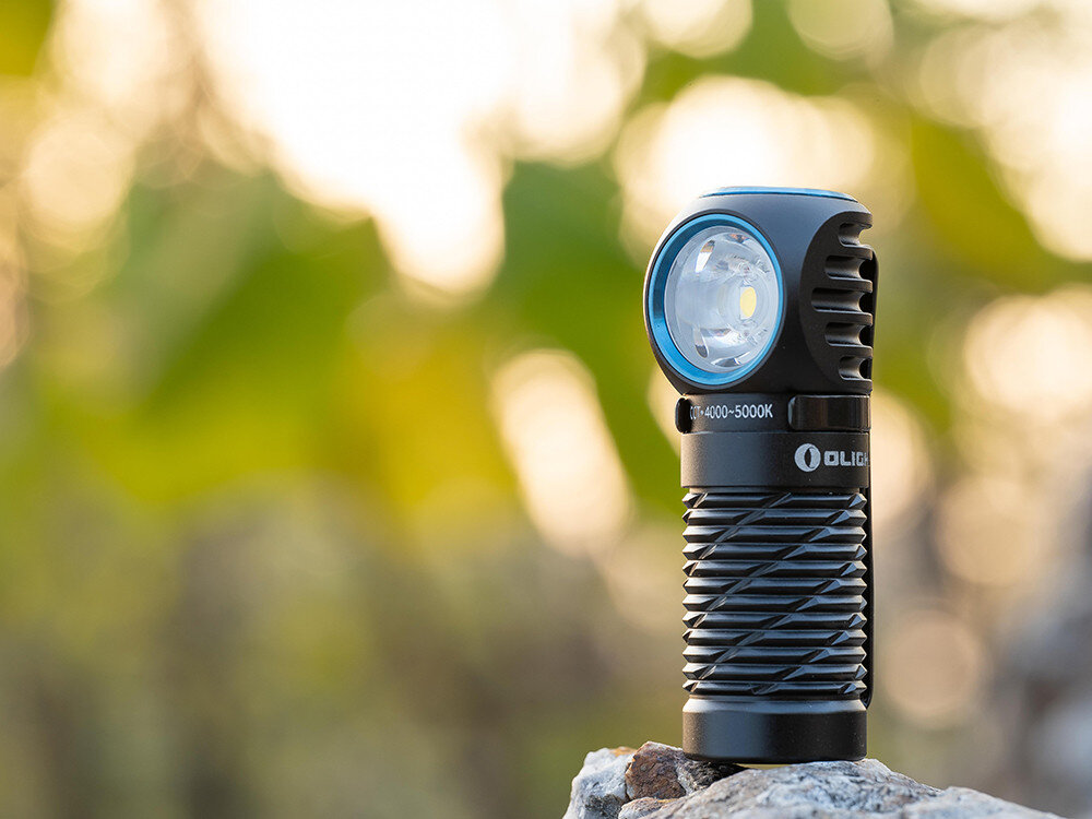 Latarka czołowa OLIGHT Perun 2 Mini QL000648, aluminium, anodyzacja, IPX8, szkło, Latarka Olight na skale, rozognione tło, jasność naturalnego światła, detale żebrowania.