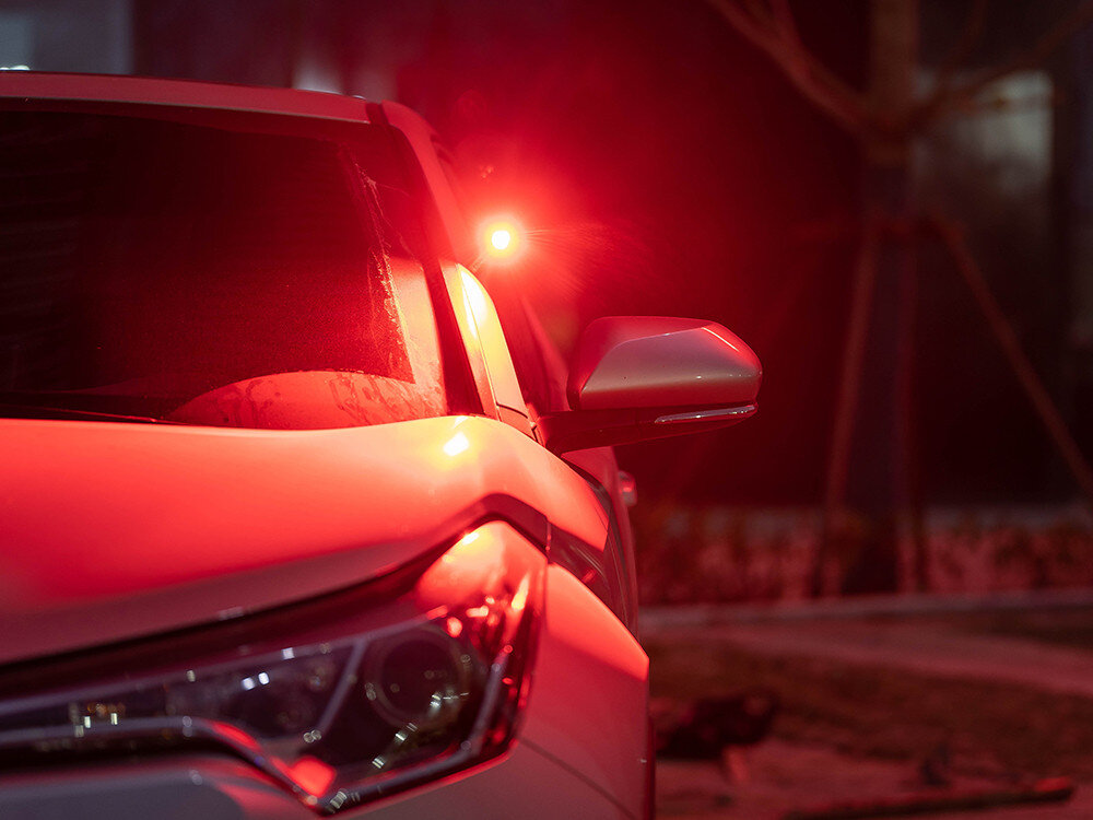 Latarka czołowa OLIGHT QL007623, magnes, klips, kieszeń, plecak, Czerwone światło awaryjne Olight na lusterku bocznym samochodu, nocna scena.