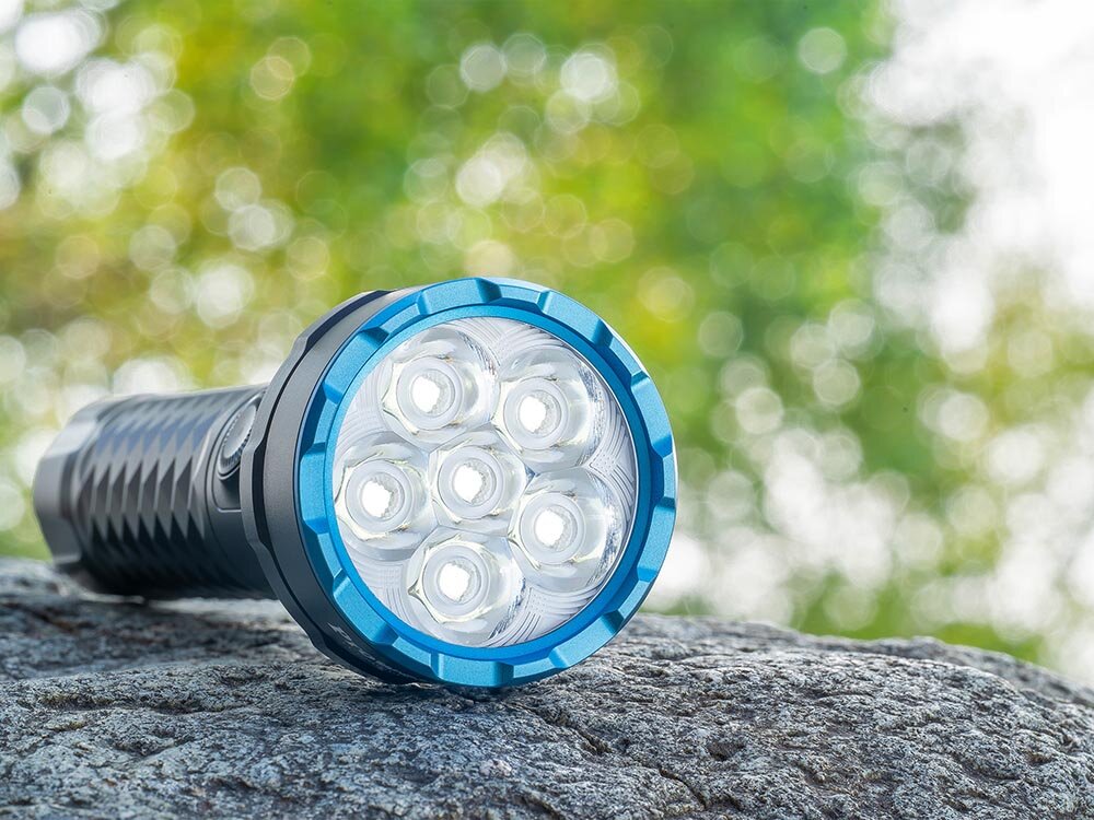 Latarka OLIGHT Prowess QL690681, Akumulator Li-Ion, 21700, 20 dni, ładowanie USB-C, Latarka Olight Prowess, siedem diod LED, niebieska głowica, leży na skale