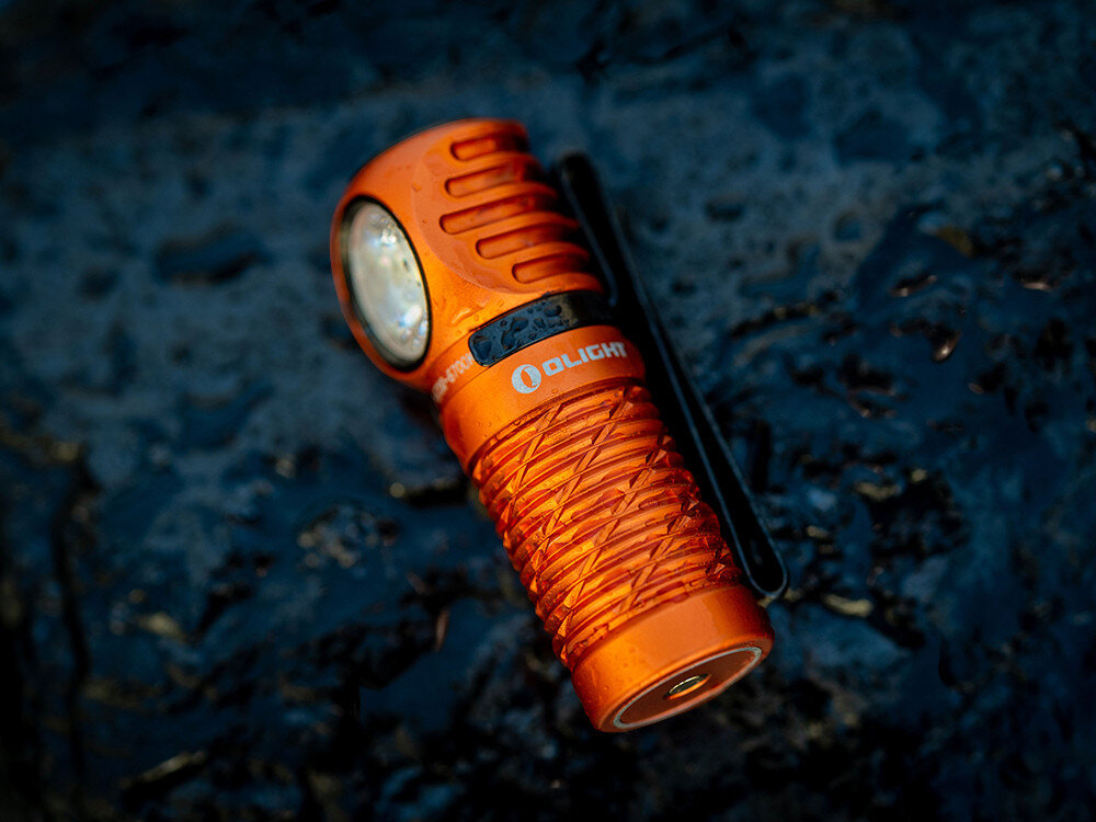 Latarka czołowa OLIGHT QL000594, aluminium, anodyzacja, IPX8, szkło, Latarka Olight na skale, rozognione tło, jasność naturalnego światła, detale żebrowania.