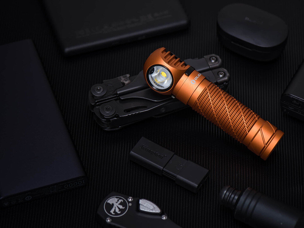 Latarka czołowa OLIGHT Perun 2 QL005063, latarka, Perun 2, światło, teren, Pomarańczowa latarka Olight na czarnym tle, w otoczeniu multitoola i narzędzi EDC, produkt solo.