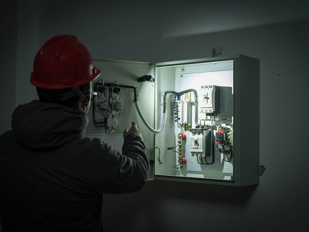 Latarka czołowa OLIGHT Perun 2 QL121745, czujnik, automatyka, jasność, ochrona, Elektryk analizuje wnętrze rozdzielni, latarka Olight montowana wewnątrz, intensywne światło.