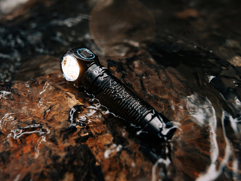 Latarka czołowa OLIGHT Perun 3 QL690193, LED, czołówka, 3000 lumenów, ergonomia, Latarka Olight jako czołówka na głowie mężczyzny, plener nocą, górskie tło, plecak.