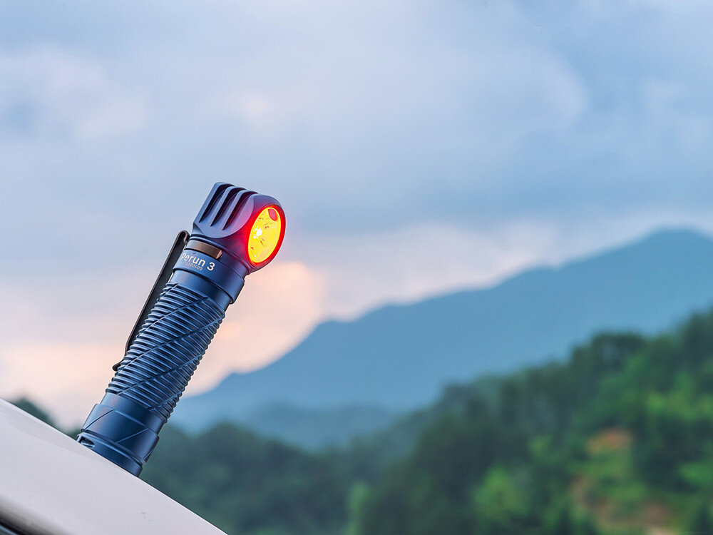 Latarka czołowa OLIGHT Perun 3 QL690490, opaska, klips, magnes, montaż, Latarka Olight Perun 3 świecąca czerwonym światłem na bagażniku auta, tło góry i niebo.