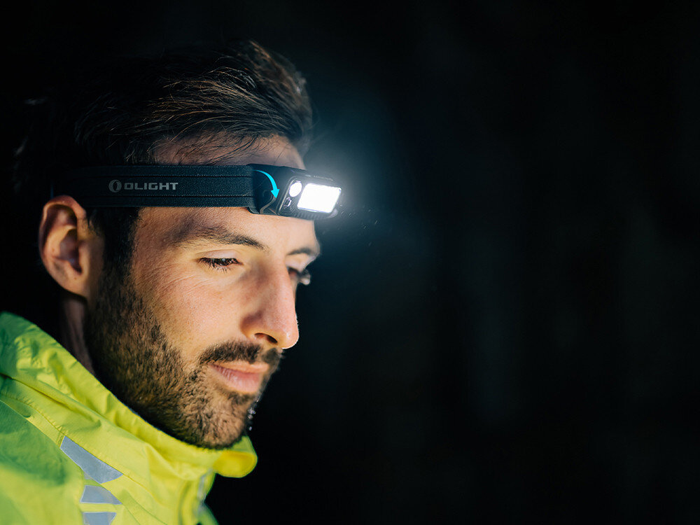 Latarka czołowa OLIGHT Array 2 Pro QL007913, gesty, bezdotyk, wygoda, kontrola, Twarz mężczyzny z jasną czołówką Olight, kurtka odblaskowa nocą, wyraziste światło LED.
