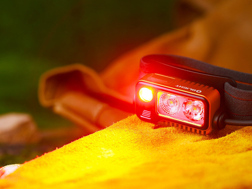 Latarka czołowa OLIGHT Array 2 Pro QL128782, czerwone światło, noc, poziomy, widoczność, Olight Array 2 Pro świeci czerwonym światłem, opaska na powierzchni tkaniny w plenerze, detale.