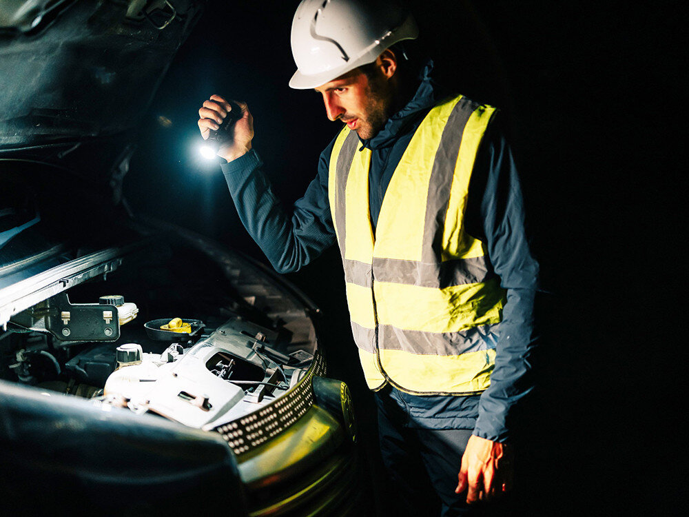 Latarka OLIGHT Seeker 4 Pro QL006169, kabura, pasek, montaż, pojazd, Technik w kamizelce i kasku sprawdza silnik samochodu latarką Olight, noc, warsztat w terenie.