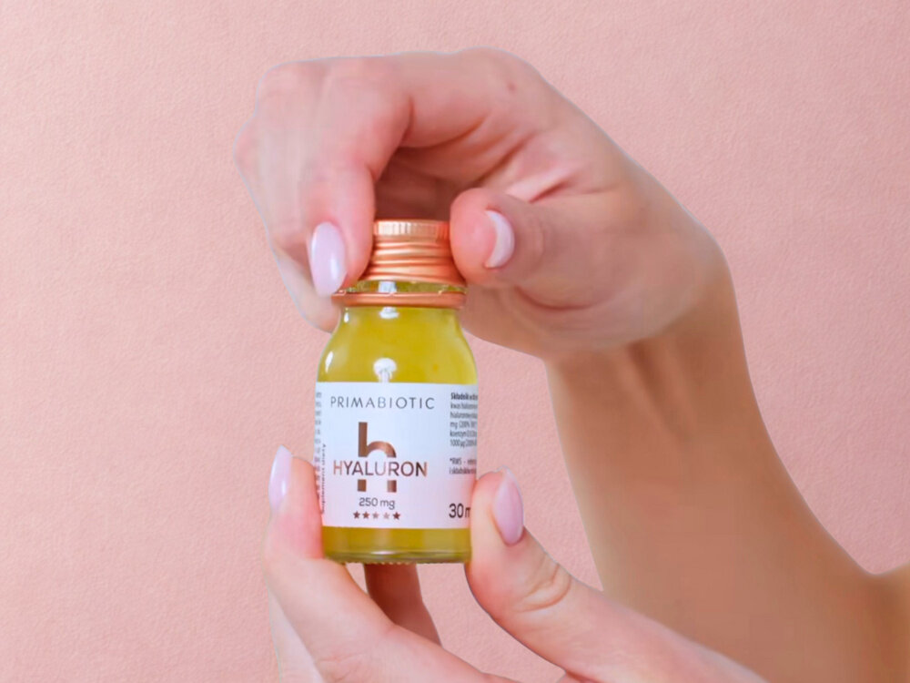 Kwas hialuronowy PRIMABIOTIC Mango 30 x 30 ml osoba trzyma buteleczkę w dłoniach różowe tło biotyna D-biotyna – 1 mg, 2000% RWS witamina piękna zdrowe włosy i paznokcie zmniejsza łamliwość i wypadanie