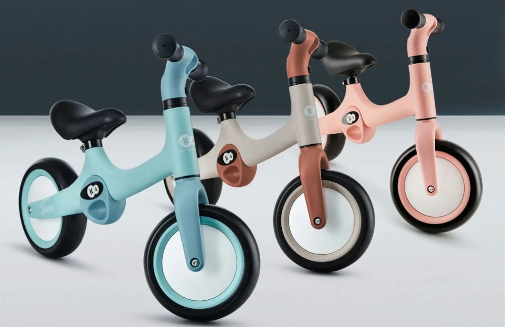 Rowerek biegowy KINDERKRAFT Tove Beżowy pierwszy rowerek ciemne tło trzy rowerki niebieski beżowy oraz różowy gumowe uchwyty ciemne koła czarne siodełka 