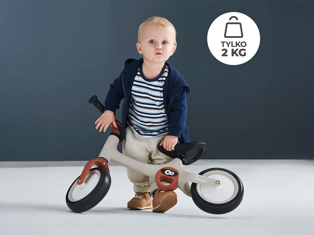 Rowerek biegowy KINDERKRAFT Tove Beżowy dziecko trzyma beżowy rowerek brązowe elementy ciemne tło trwałość lekkość z wytrzymałych materiałów tworzywa PP i TPR waży jedynie 2 kg poręczny łatwe podnoszenie i przenoszenie zabranie w podróż wytrzymałość funkcjonalność wygoda użytkowania 