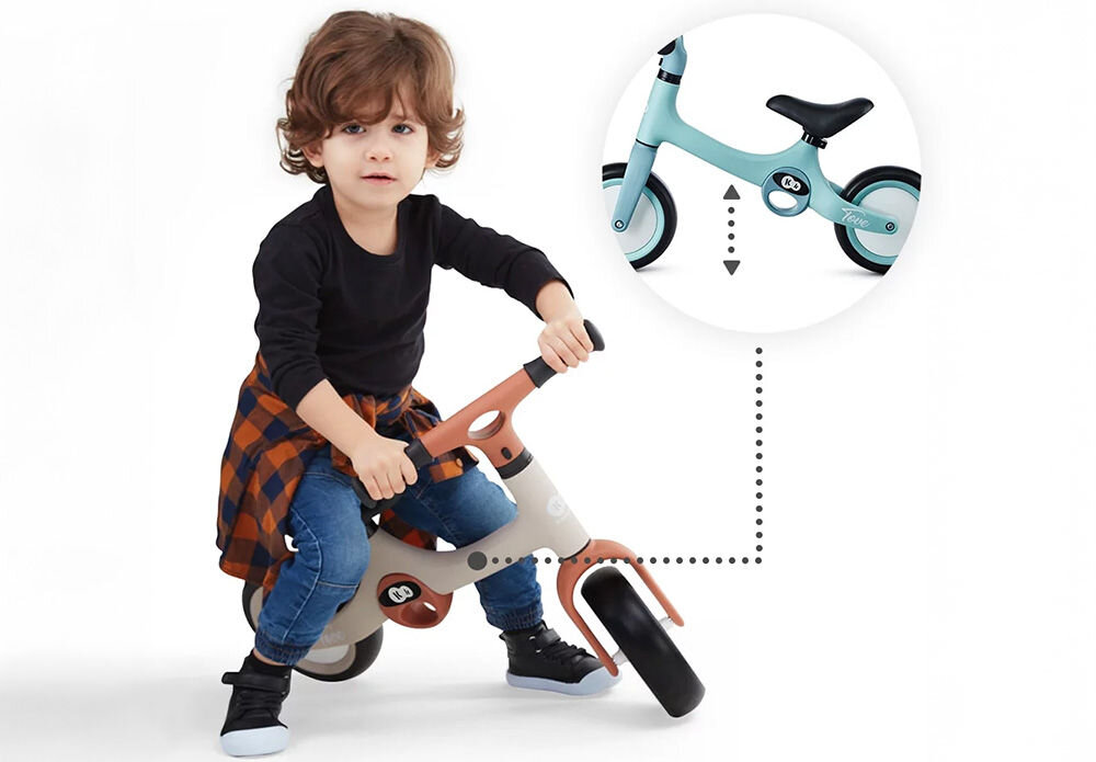 Rowerek biegowy KINDERKRAFT Tove Beżowy dziecko jedzie na rowerku łapanie równowagi białe tło świetna zabawa kluczowy etap w rozwoju dziecka doskonalenie równowagi koordynacji ruchowej i sprawności fizycznej naturalny pełen radości proces intuicyjny swobodny proces rozwijania umiejętności 