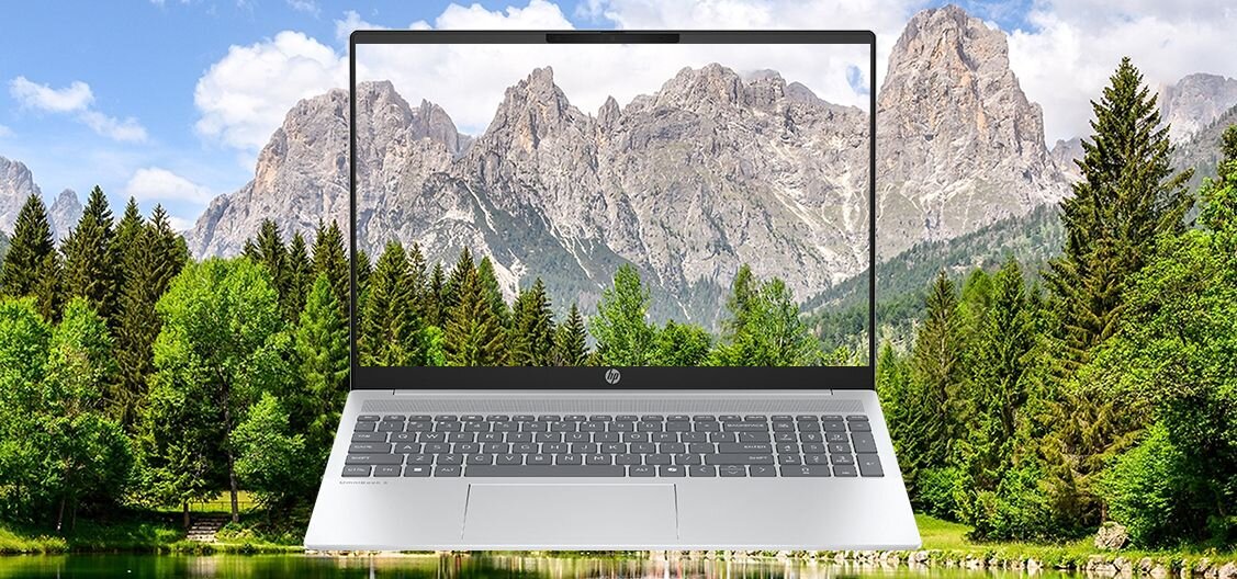 Laptop HP OmniBook 5 16-BC1 z panoramą górskiego krajobrazu na ekranie na tle prawdziwych gór i lasu - Materiały z recyklingu, ocean-bound plastics