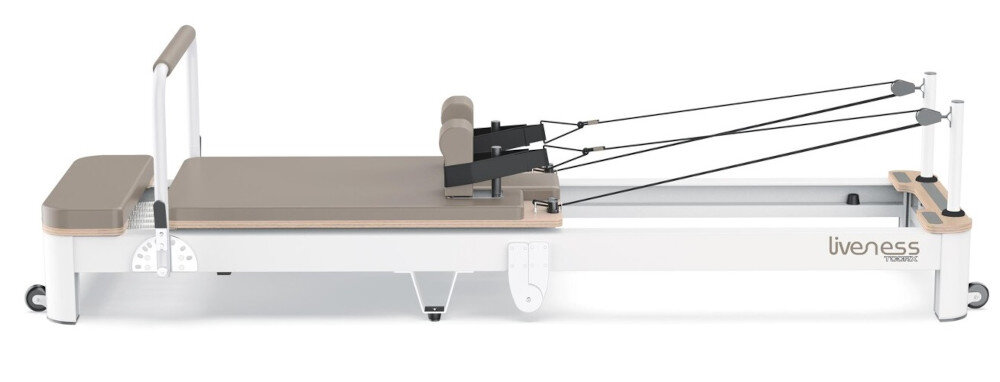 Reformer do pilatesu z napisem \'liveness TOORX\' na boku, wyposażony w platformę, poduszki i system lin z uchwytami.