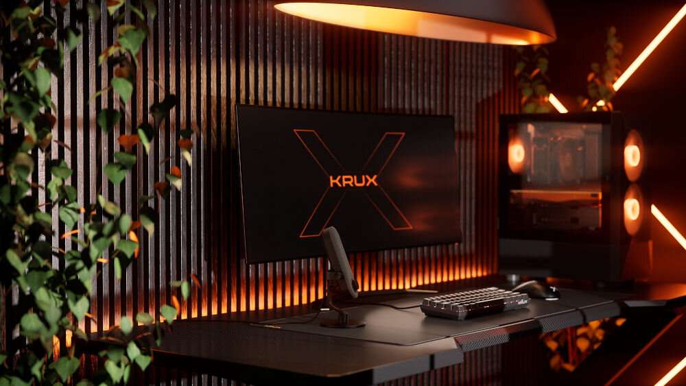 Mikrofon KRUX Pin KRXC018 Kardioidalny Czarny Pełne ujęcie stanowiska gamingowego z mikrofonem KRUX Pin na pierwszym planie, monitor z logo KRUX w tle, oświetlenie RGB w odcieniach pomarańczowo-czerwonych oraz bujna roślina po lewej stronie