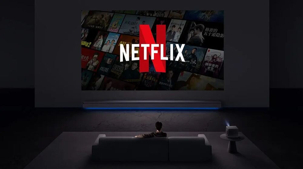 Projektor XGIMI Horizon 20 Max licencja Netflix aplikacja Netflix pilot szybki dostęp streaming, osoba siedząca na kanapie przed obrazem wyświetlanym przez projektor