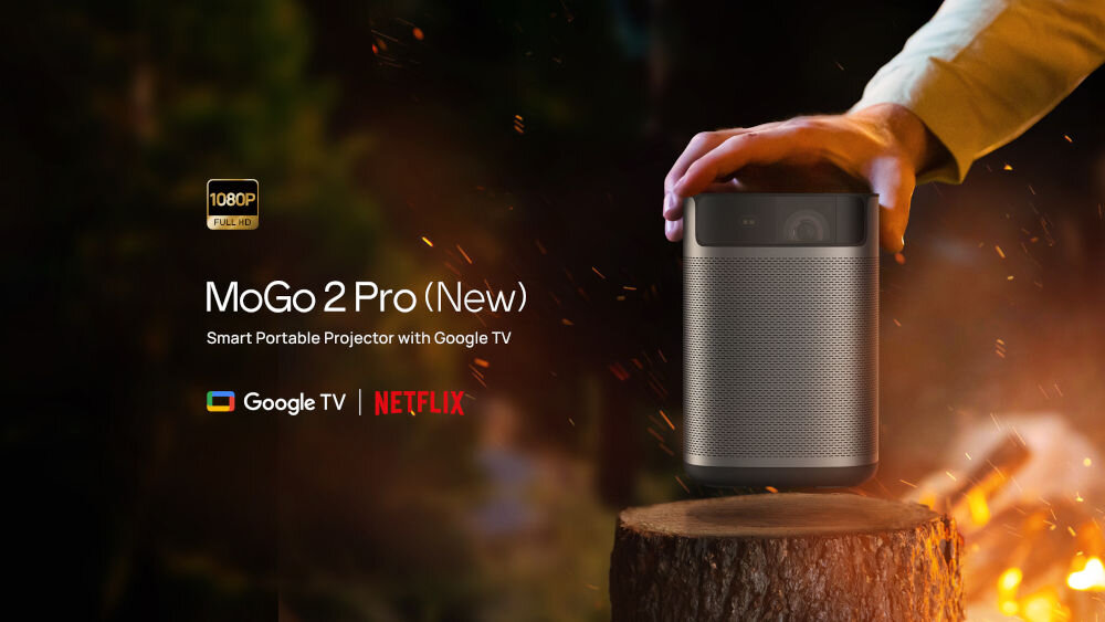 Projektor XGIMI Mogo 2 Pro wrażenia audiowizualne Full HD 200 cali 430 ISO lumenów Google TV, urządzenie kładzione na pieńku drzewa przy ognisku